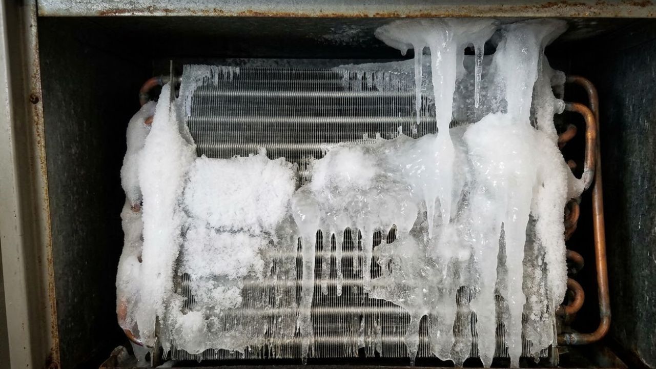 Frozen evaporator coil inside an indoor AC air handler, caused by restricted airflow or low refrigerant